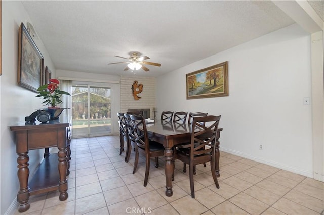 tiled dining area featuring ceiling fan and a brick fireplace