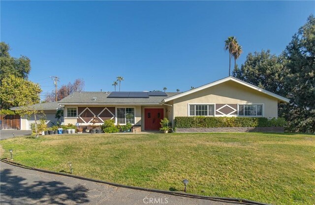 ranch-style home with a front lawn and solar panels