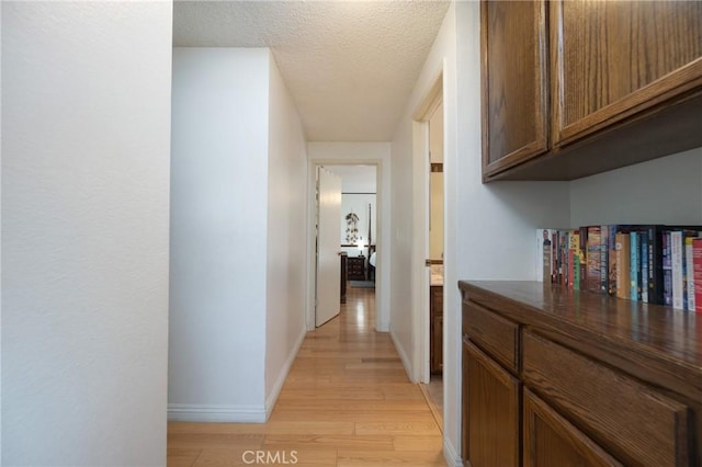 hallway featuring a textured ceiling and light hardwood / wood-style flooring