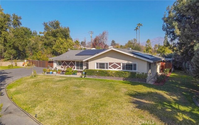 single story home with solar panels and a front yard