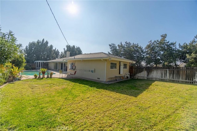 back of house featuring a patio area, a fenced in pool, and a lawn