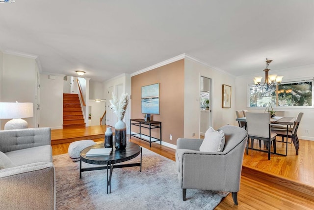 living room with a chandelier, ornamental molding, and light hardwood / wood-style floors