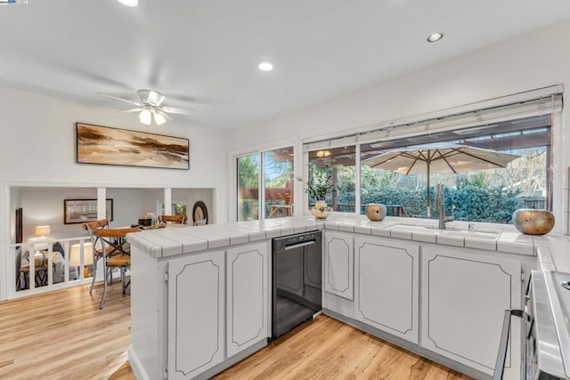 kitchen with light hardwood / wood-style floors, white cabinetry, sink, kitchen peninsula, and tile countertops