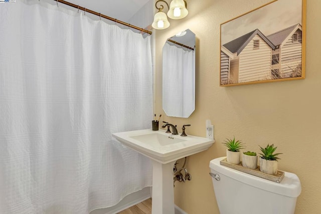 bathroom with sink, hardwood / wood-style floors, toilet, and curtained shower