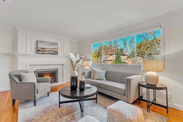 living room with a brick fireplace, ornamental molding, and light hardwood / wood-style floors