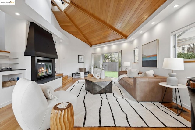 living room featuring a large fireplace, light hardwood / wood-style flooring, a towering ceiling, and wood ceiling