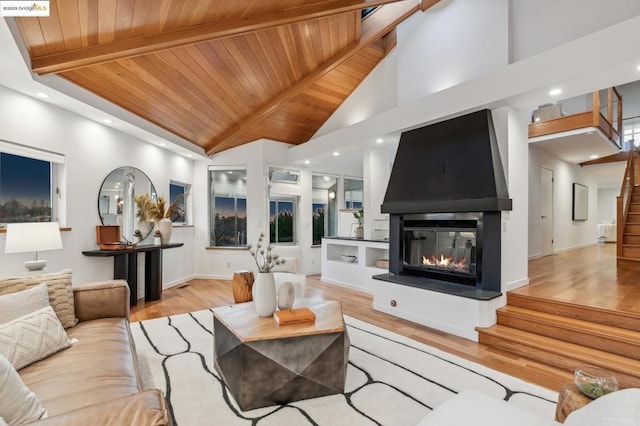 living room with a high ceiling, light hardwood / wood-style flooring, beam ceiling, and wood ceiling