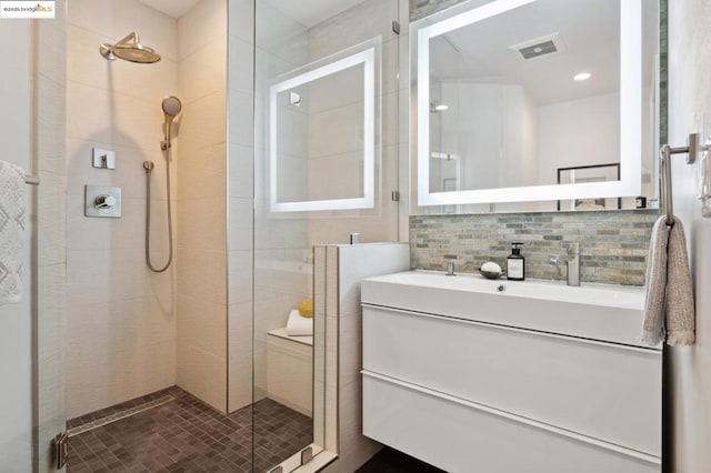 bathroom featuring backsplash, tiled shower, and vanity