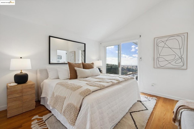 bedroom with hardwood / wood-style flooring, vaulted ceiling, and access to outside