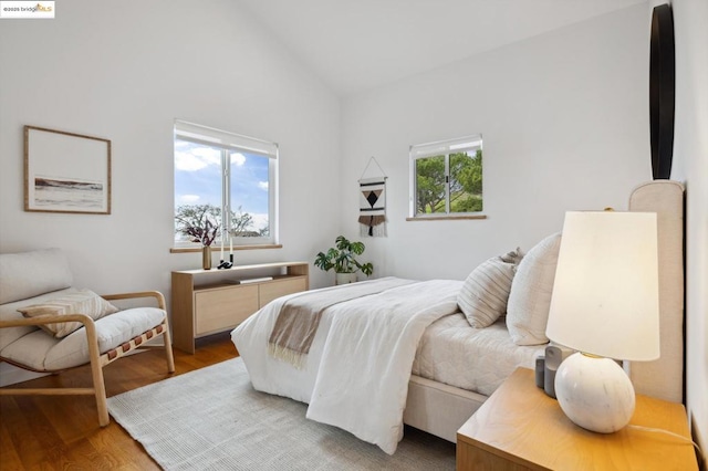 bedroom featuring high vaulted ceiling, hardwood / wood-style floors, and multiple windows