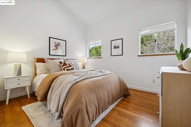 bedroom with high vaulted ceiling and hardwood / wood-style floors