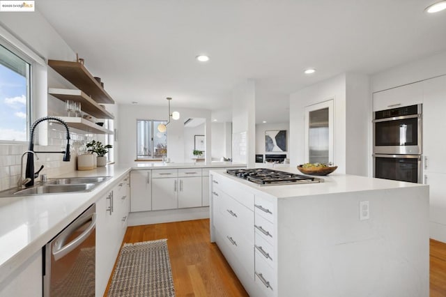 kitchen with appliances with stainless steel finishes, white cabinets, decorative light fixtures, sink, and a healthy amount of sunlight