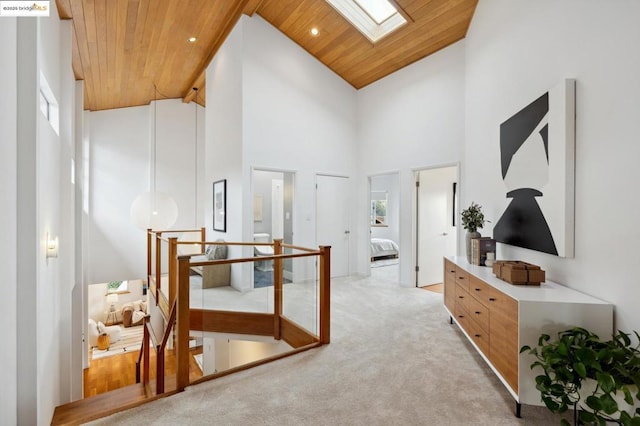 hallway featuring wood ceiling, light carpet, beamed ceiling, a skylight, and high vaulted ceiling