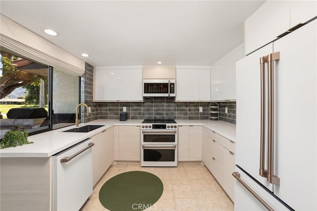 kitchen featuring decorative backsplash, sink, white appliances, and white cabinets