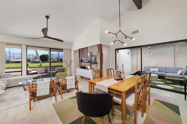 dining room featuring ceiling fan with notable chandelier and high vaulted ceiling