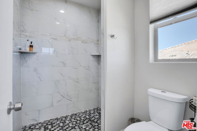 bathroom featuring tiled shower and toilet