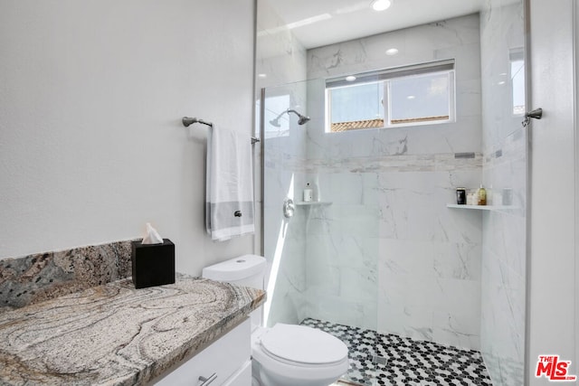 bathroom with toilet, vanity, and a tile shower