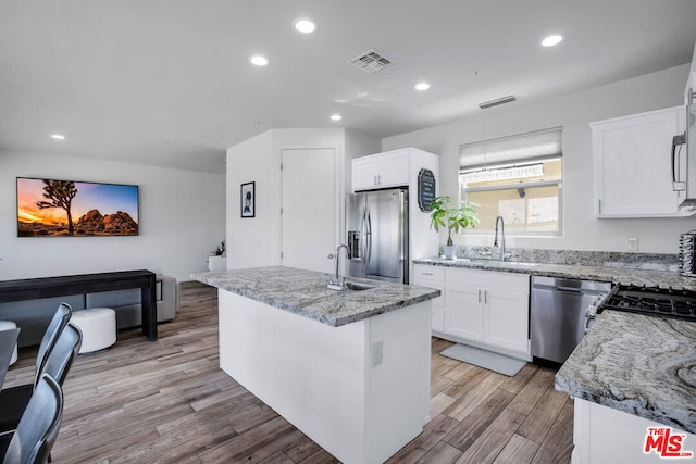 kitchen featuring white cabinets, appliances with stainless steel finishes, a center island, and sink