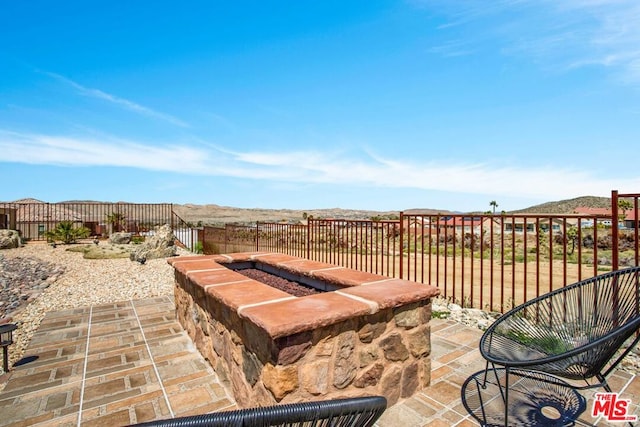 view of patio / terrace with a mountain view and a fire pit