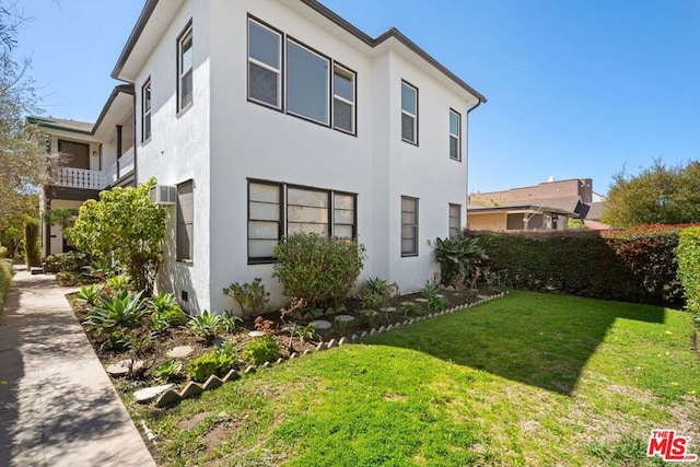 view of side of property featuring an AC wall unit and a yard