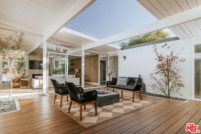 wooden terrace with an outdoor living space with a fire pit