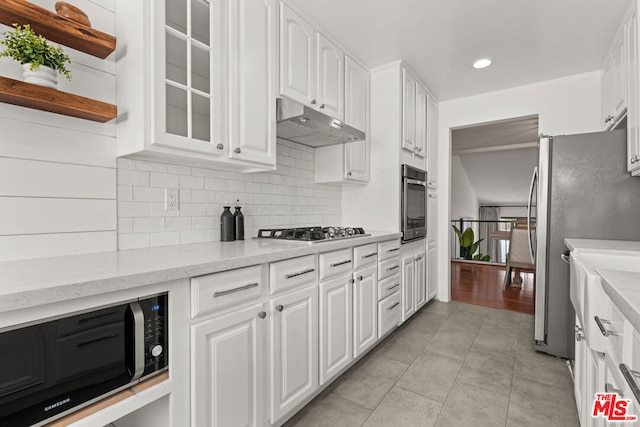 kitchen with backsplash, white cabinetry, light stone countertops, and appliances with stainless steel finishes