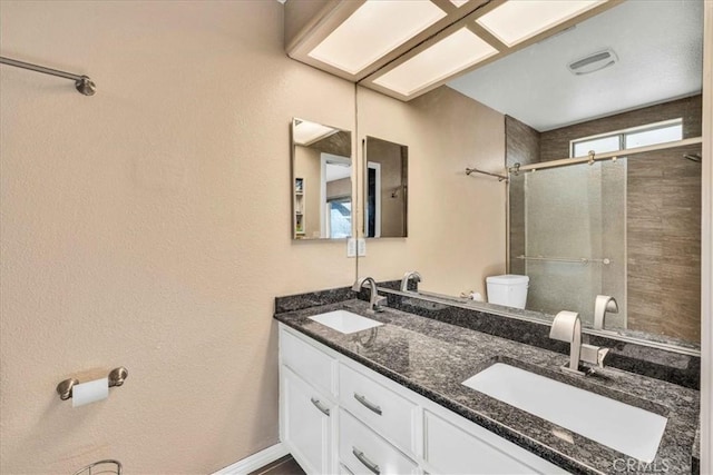 bathroom featuring vanity, toilet, and a shower with door