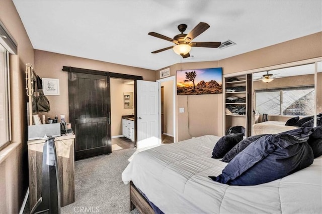 bedroom featuring a closet, ceiling fan, a barn door, and carpet floors