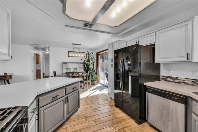 kitchen featuring black fridge with ice dispenser, visible vents, light countertops, stainless steel dishwasher, and light wood-type flooring