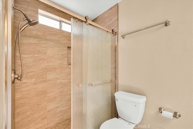 bathroom featuring toilet and a shower with door