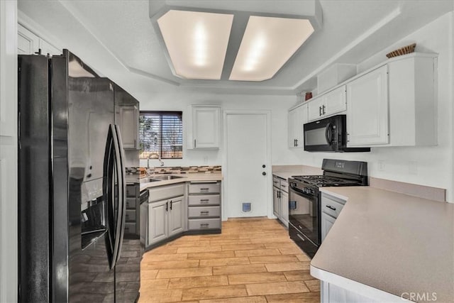 kitchen featuring sink, white cabinets, black appliances, and light hardwood / wood-style flooring