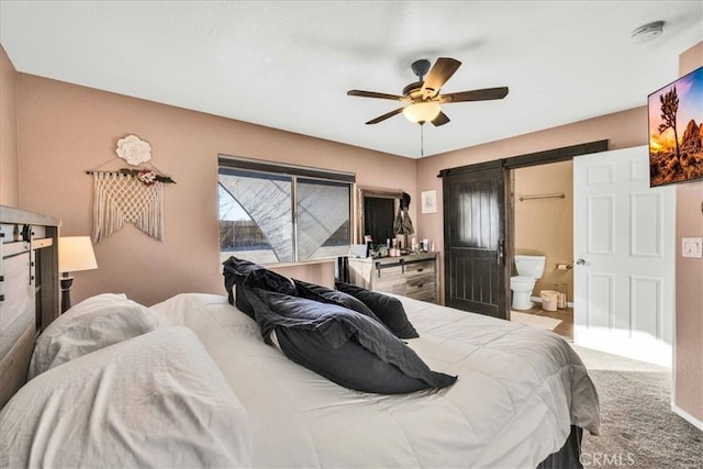 bedroom with ceiling fan, ensuite bathroom, a barn door, and light carpet