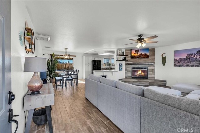 living area featuring ceiling fan, a fireplace, and wood finished floors