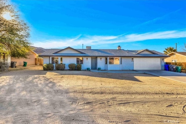 ranch-style house featuring a chimney, stucco siding, concrete driveway, an attached garage, and fence