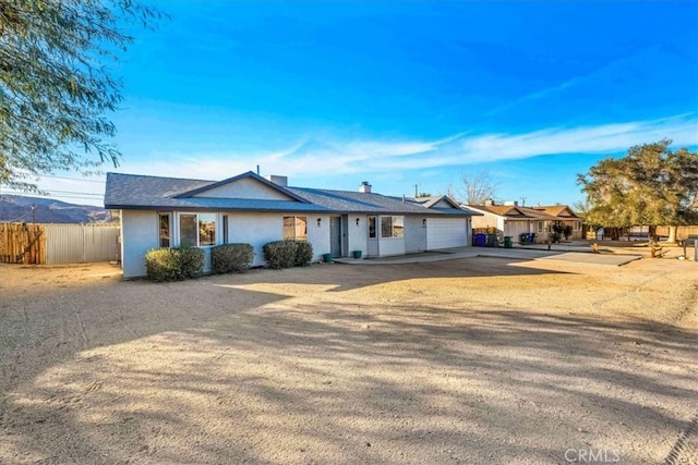 ranch-style home with a garage, a chimney, fence, and concrete driveway