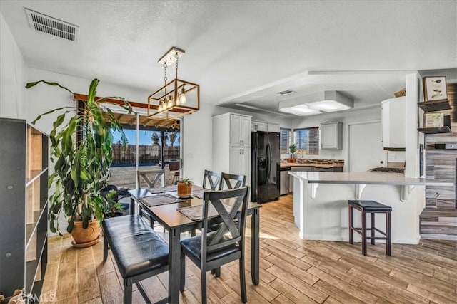 dining room featuring a textured ceiling, light wood-style flooring, and visible vents