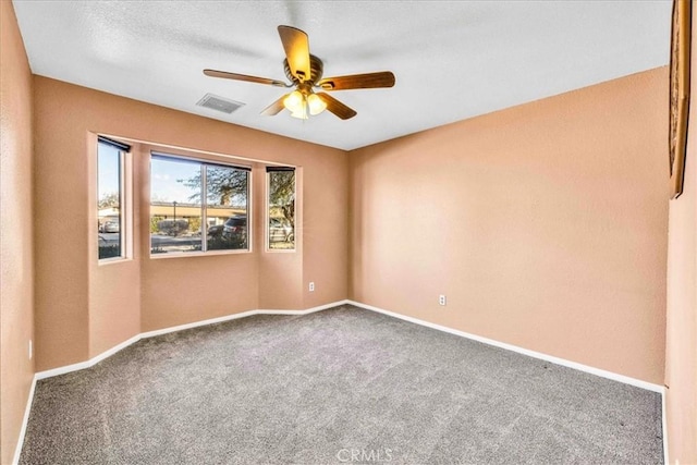 empty room featuring a ceiling fan, carpet, visible vents, and baseboards