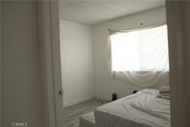 bedroom with light hardwood / wood-style floors and a textured ceiling