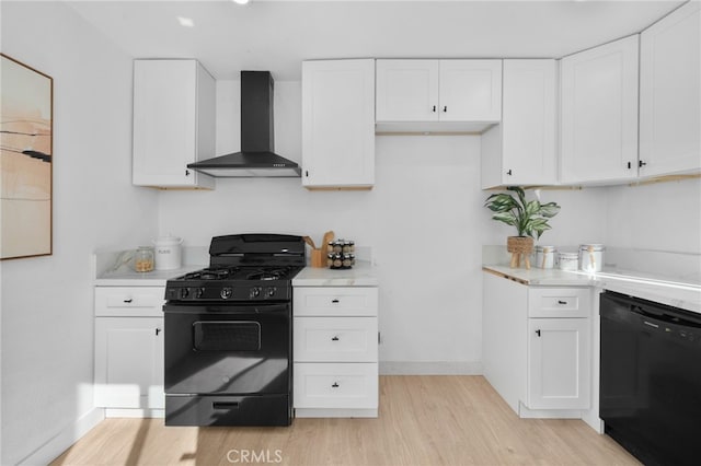 kitchen featuring wall chimney range hood, black appliances, light hardwood / wood-style floors, and white cabinets