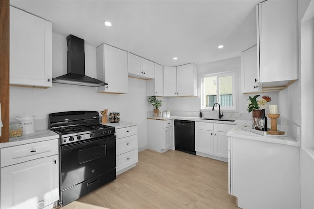 kitchen with sink, white cabinets, wall chimney exhaust hood, black appliances, and light hardwood / wood-style flooring