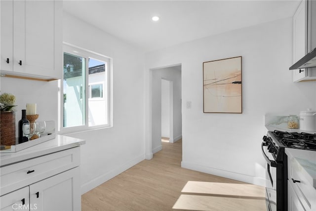 kitchen featuring light hardwood / wood-style floors, white cabinets, and black gas stove