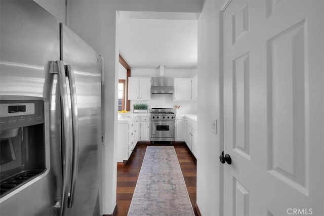 kitchen featuring stainless steel appliances, dark wood-type flooring, wall chimney range hood, and white cabinets