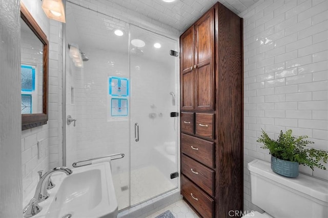 bathroom featuring sink, tile walls, an enclosed shower, toilet, and tile patterned floors