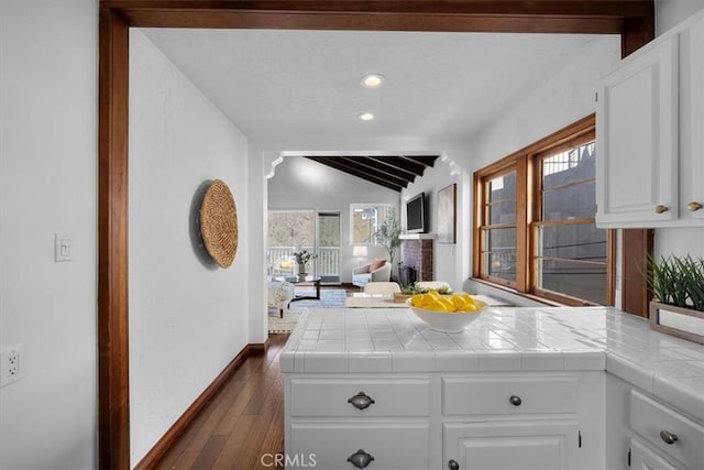 kitchen featuring vaulted ceiling with beams, plenty of natural light, tile counters, and white cabinets