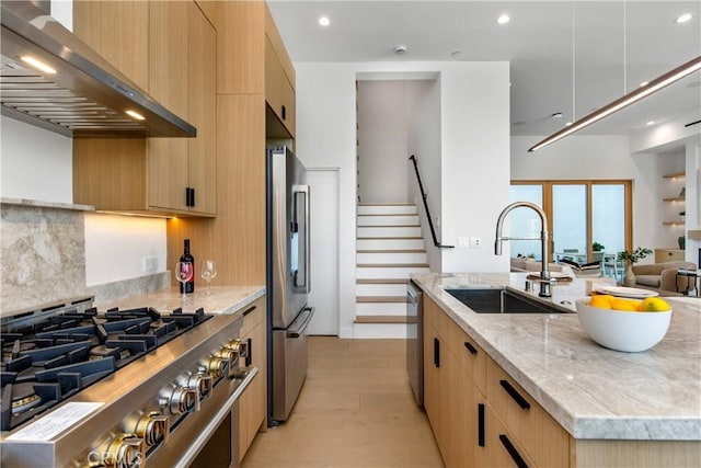 kitchen featuring sink, light stone counters, premium appliances, an island with sink, and exhaust hood