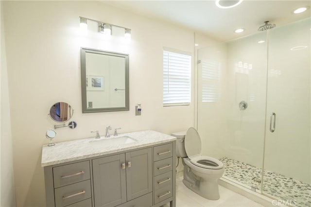 bathroom featuring tile patterned flooring, vanity, a shower with shower door, and toilet