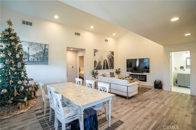 dining area with a towering ceiling and light hardwood / wood-style floors