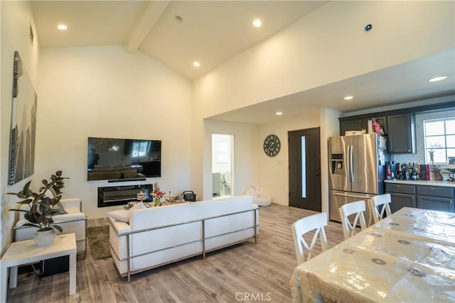 living room featuring beam ceiling, high vaulted ceiling, and light hardwood / wood-style flooring