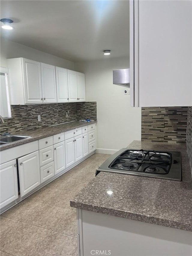 kitchen with tasteful backsplash, sink, white cabinets, and range