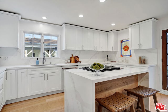 kitchen featuring white dishwasher, a center island, white cabinets, and a kitchen bar